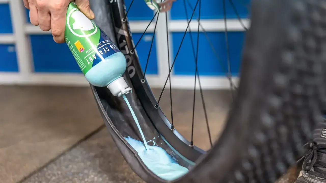 Flüssigkeit wird in einen MTB-Reifen gegossen, um ihn für den Tubeless-Betrieb vorzubereiten. Das ist ein wichtiger Schritt beim MTB Reifen wechseln.