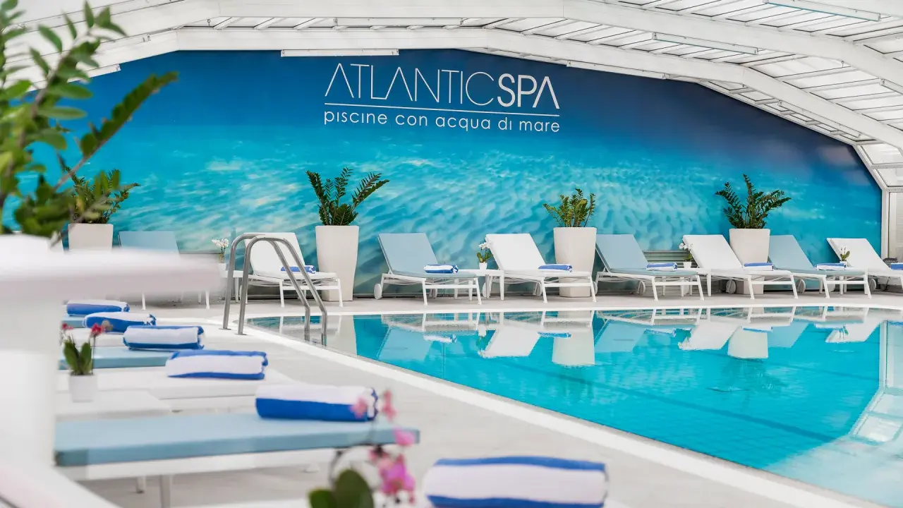 Rilassati nei bagni Riccione con piscina, un'oasi di benessere con lettini e teli blu.