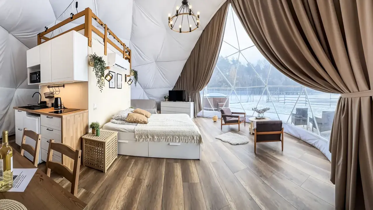 Przytulny glamping w Wielkopolsce: domek z aneksem kuchennym, wygodnym łóżkiem i widokiem na zimowy krajobraz.