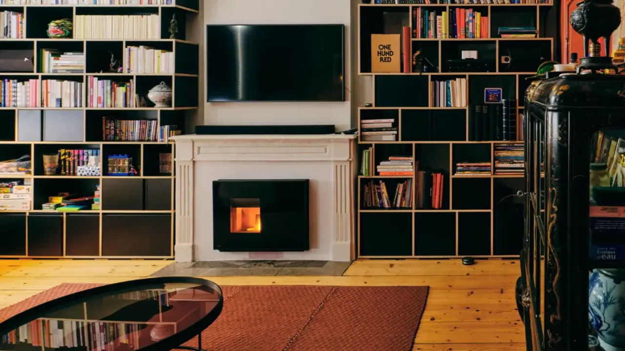 Salon cosy avec cheminée et insert à pellets silencieux, entouré d'étagères remplies de livres.