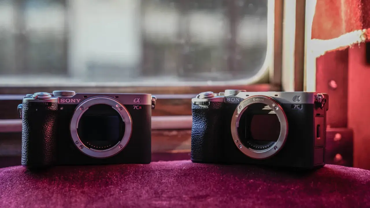 Dwa aparaty Sony Alpha, jeden a7c i drugi a7CR, leżą obok siebie na aksamitnym materiale.