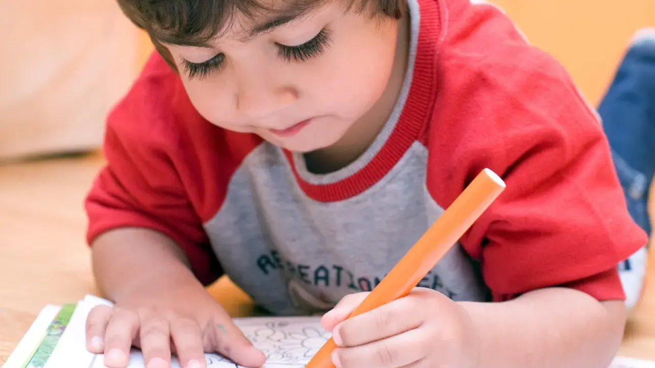 Bambino concentrato colora un disegno. A che età si capisce se un bambino è iperattivo? Osservare la sua attenzione e calma.
