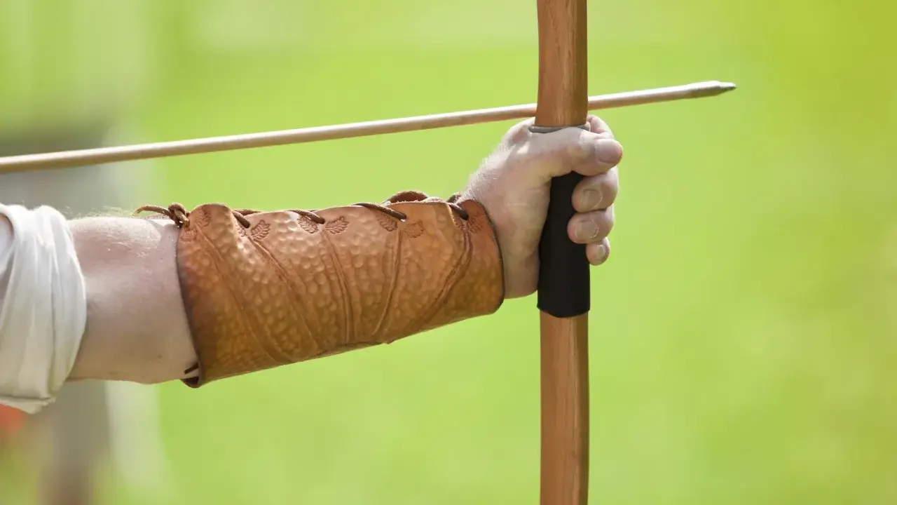 Mano con bracciale in cuoio, pronta a scoccare una freccia con l'arco, come un bellosguardo robin hood.