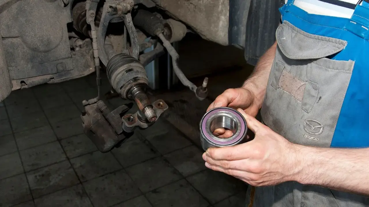 Mechanik trzyma nowe łożysko, przygotowując się do wymiany. Oto jak sprawdzić łożysko w kole przednim.