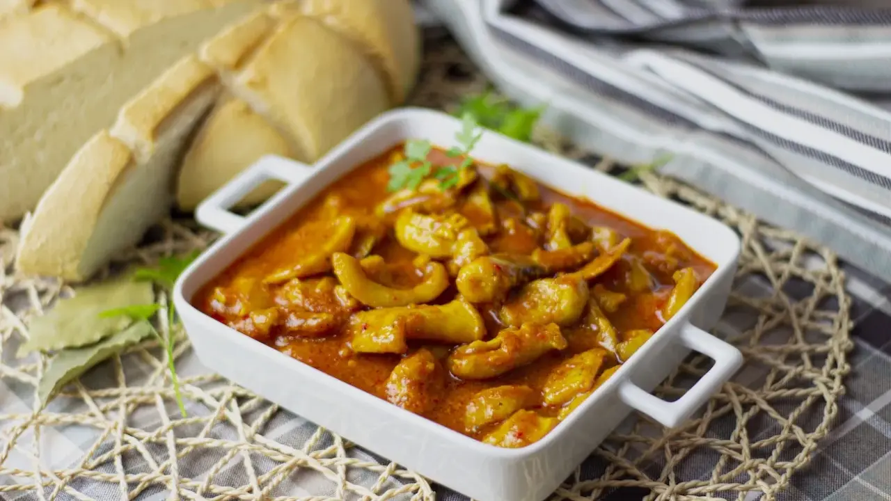 Deliciosa jibia en salsa, servida en un cuenco blanco, acompañada de pan rústico y decorada con perejil.