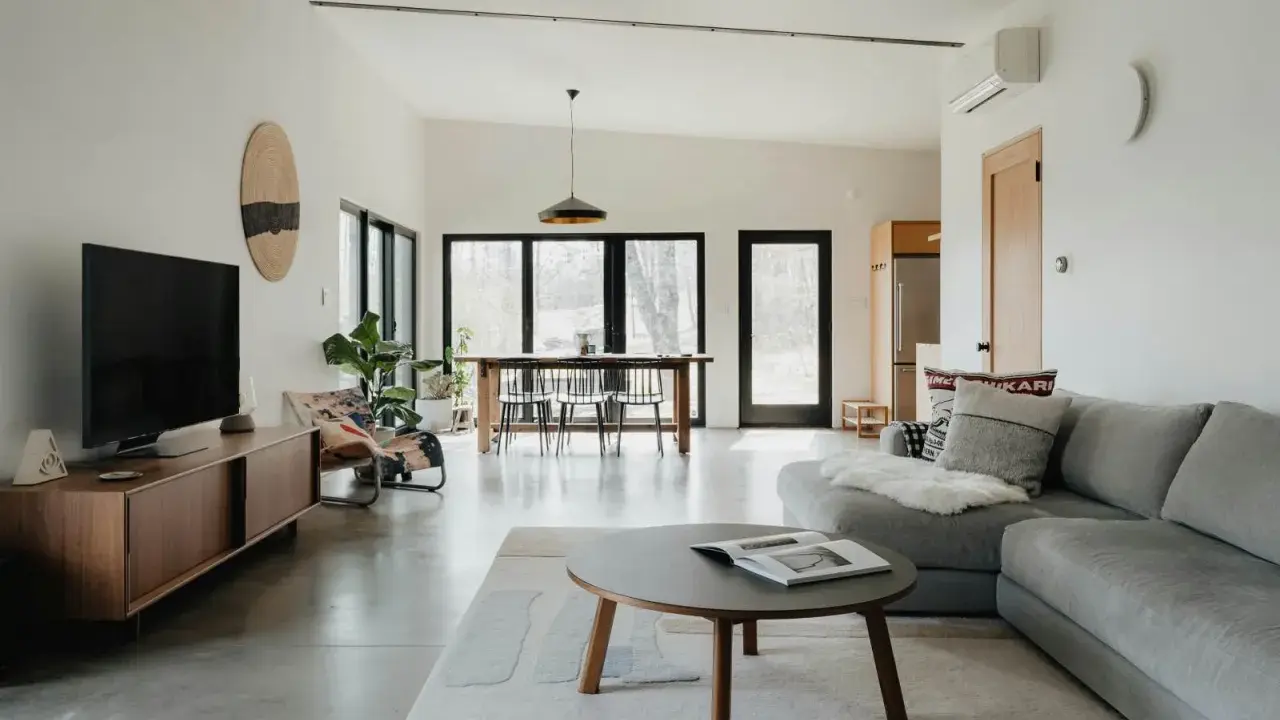 Salón moderno con sofá gris, mesa de centro y comedor. El color gris se combina con tonos madera y blanco, creando un ambiente sereno.