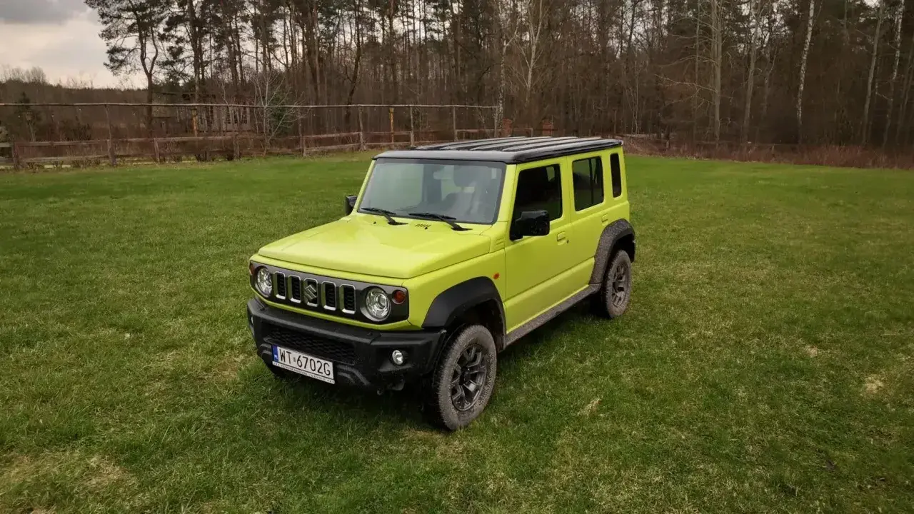 Jaskrawozielony Suzuki Jimny 5-drzwiowy na trawie. Sprawdź jego cenę i możliwości terenowe!