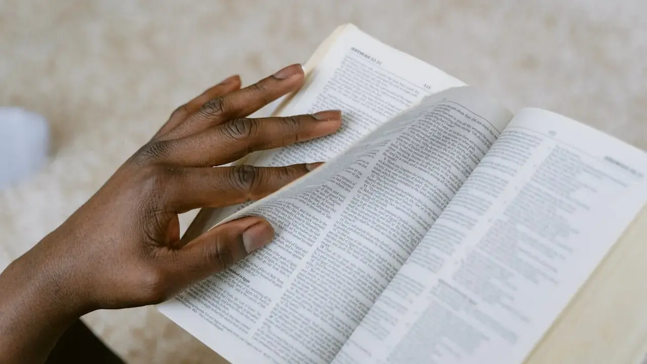 Dłoń przewracająca strony Biblii, szukająca pocieszenia w Psalmie 27.