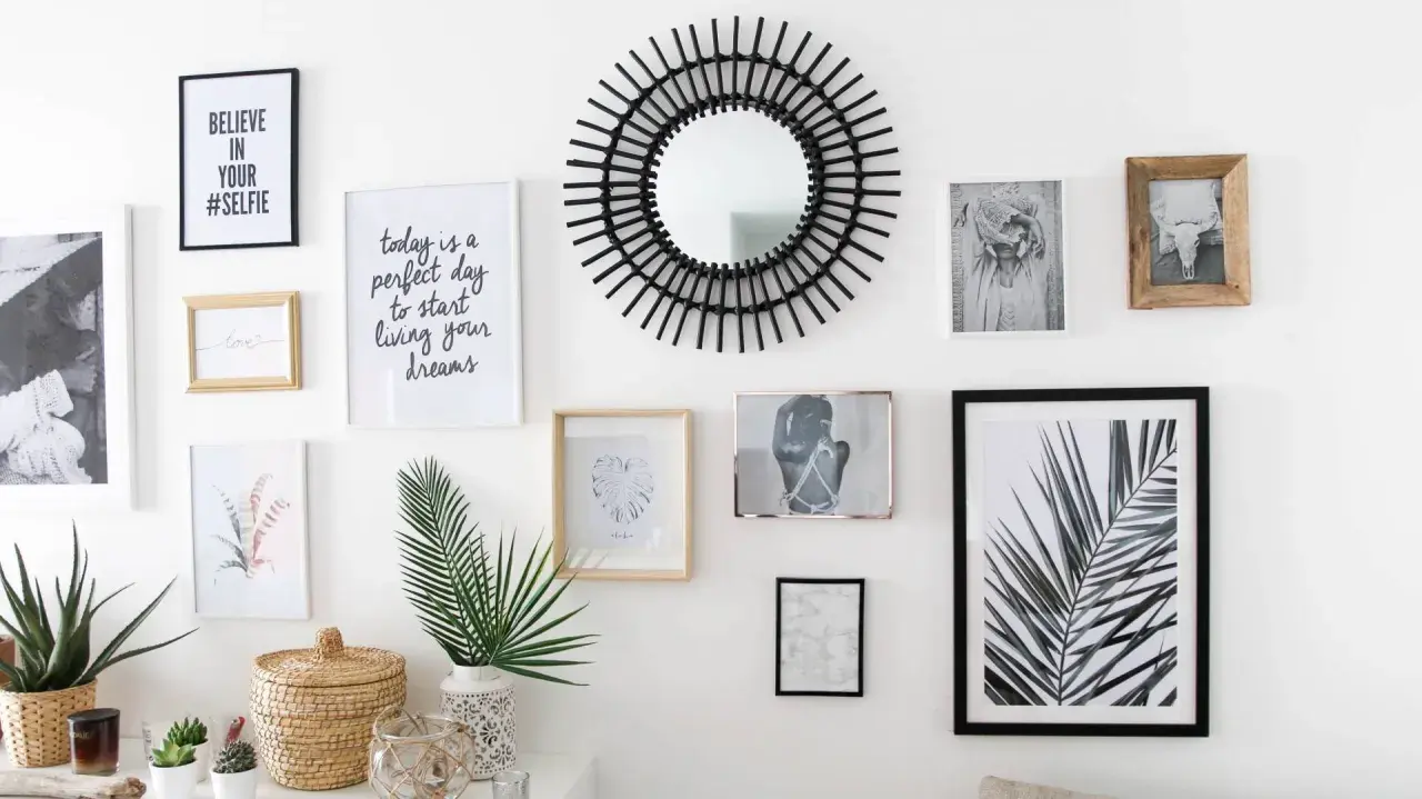 Un mur de cadres éclectique avec un miroir soleil, des photos et des citations inspirantes.