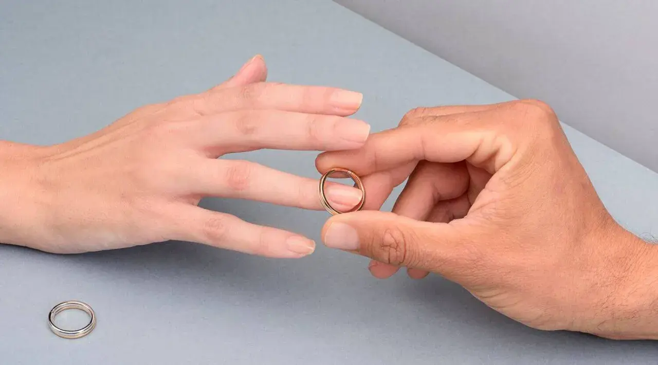 Manos unidas, un anillo dorado listo para ser colocado en el dedo anular, el lugar donde se pone el anillo de compromiso.