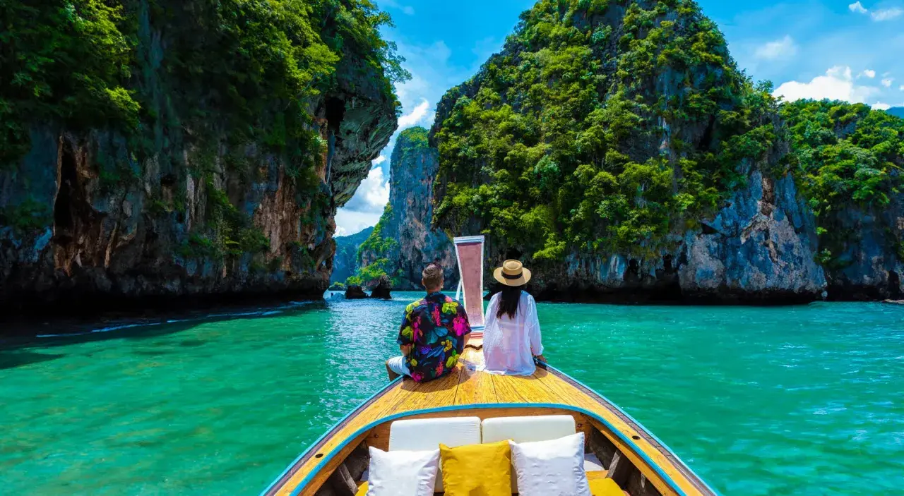 Para w łodzi podziwia turkusową wodę i skaliste wyspy. Idealna pogoda na Phuket w grudniu.