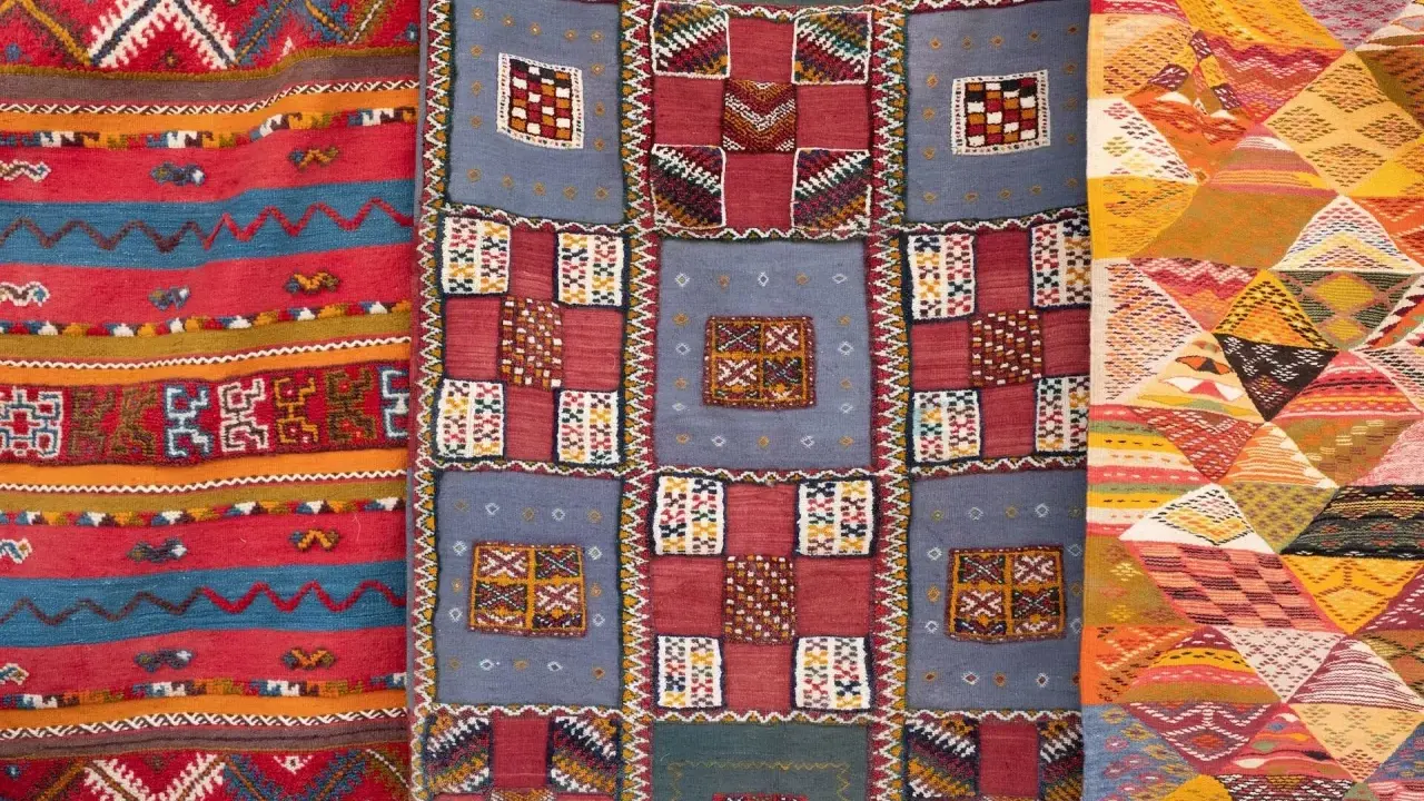 Bunte Teppiche mit geometrischen Mustern, die das orientalische Flair widerspiegeln. Ein Teppich zeigt Streifen, ein anderer Quadrate und das dritte Rauten.
