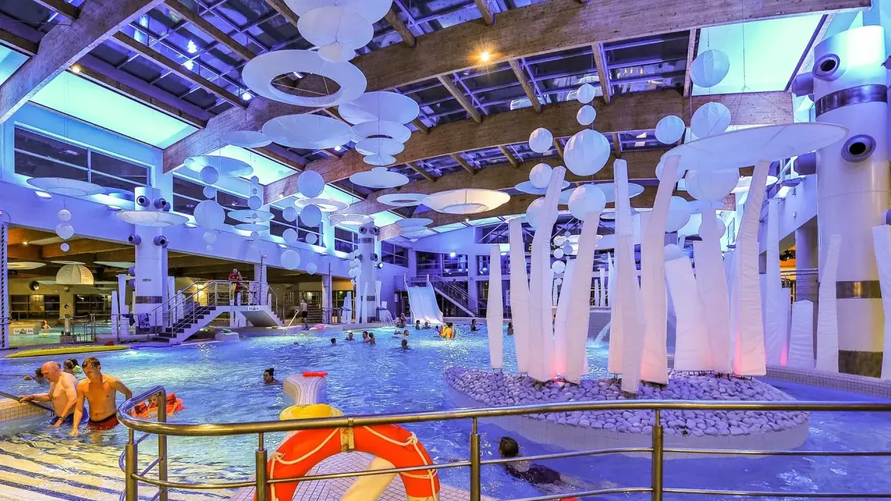 Wesoła zabawa w aquaparku w Sopocie, mnóstwo ludzi cieszy się basenem i atrakcjami. Warto sprawdzić aquapark Sopot opinie przed wizytą.