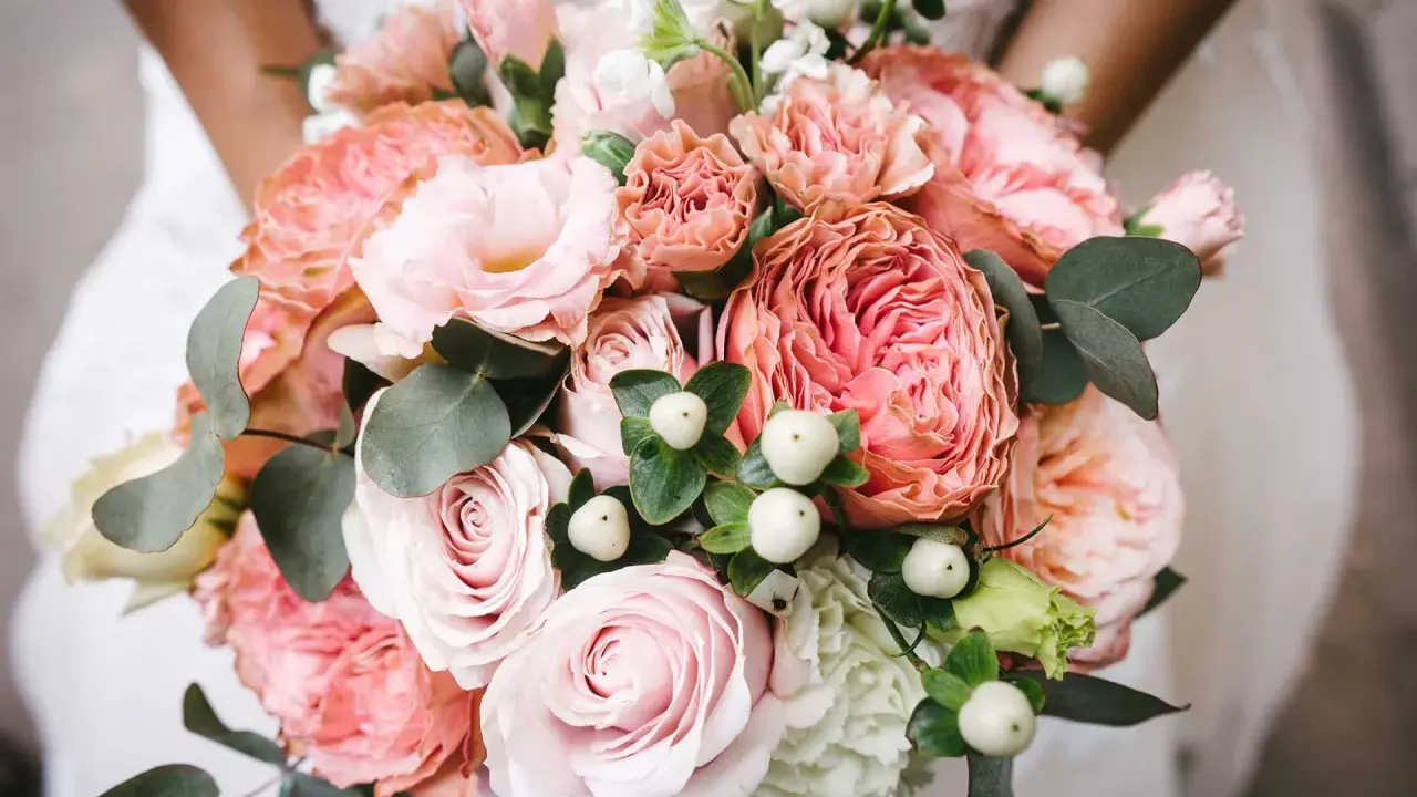 En vacker bukett med rosa rosor, nejlikor och eukalyptus. Perfekta blommor till dukning för ett romantiskt bröllop.