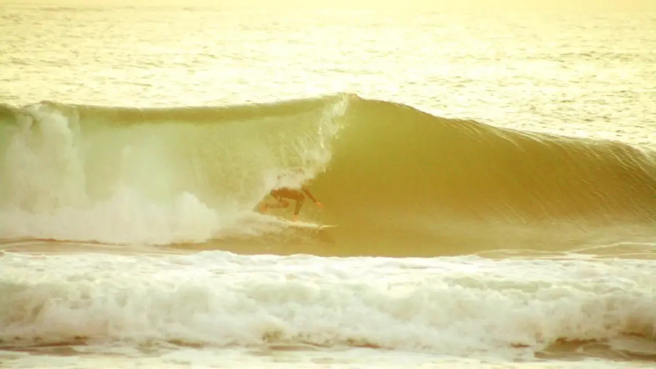 Surfer reitet eine Welle im goldenen Licht. Ein perfekter Moment beim el palmar surfen.