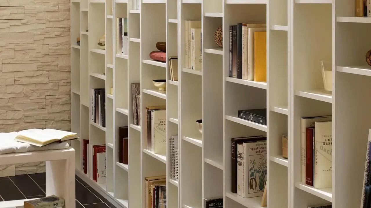 Eine weiße, modulare Bücherwand, perfekt für dein Projekt "Bibliothek selber bauen". Viele Bücher und Deko-Objekte sind ordentlich einsortiert.
