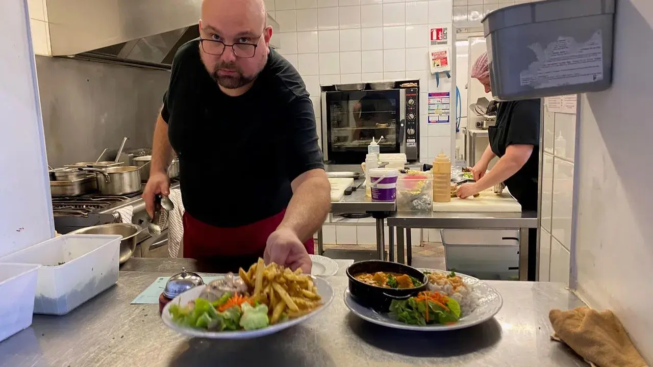 Un chef présente des assiettes de frites, salade et curry, des spécialités normandie.