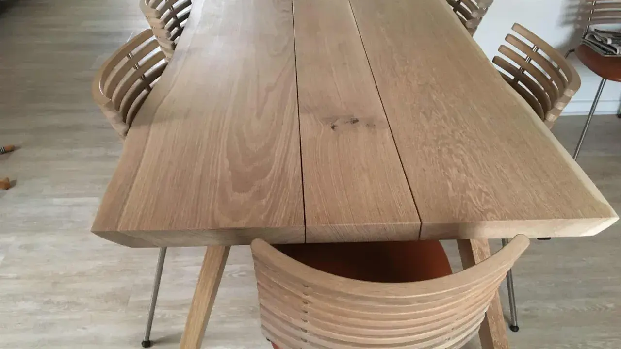 Oljat ekbord med ljusare träyta och moderna stolar med träribbor.