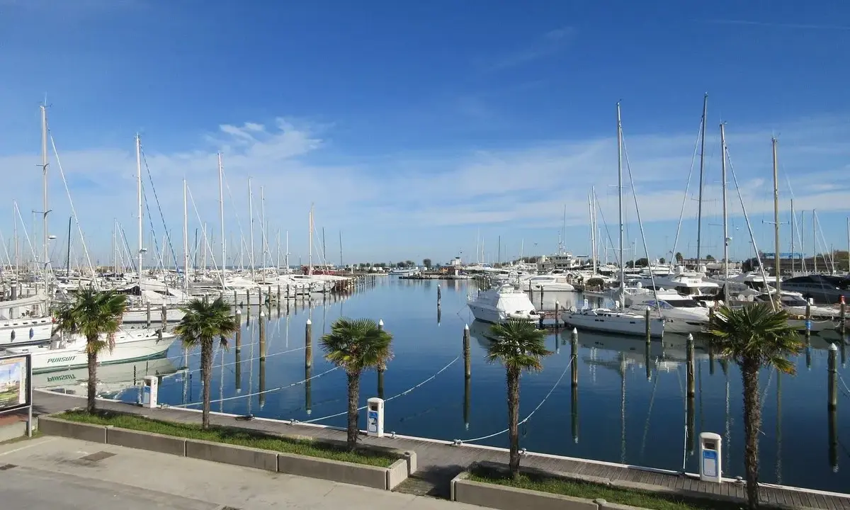 Porto turistico di San Giuliano Mare, Rimini, con barche a vela e yacht ormeggiati in un mare calmo sotto un cielo azzurro.