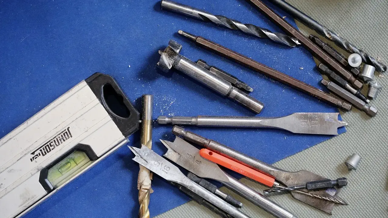 Niveau à bulle et divers outils du maçon, incluant des forets et des mèches, prêts pour le travail.