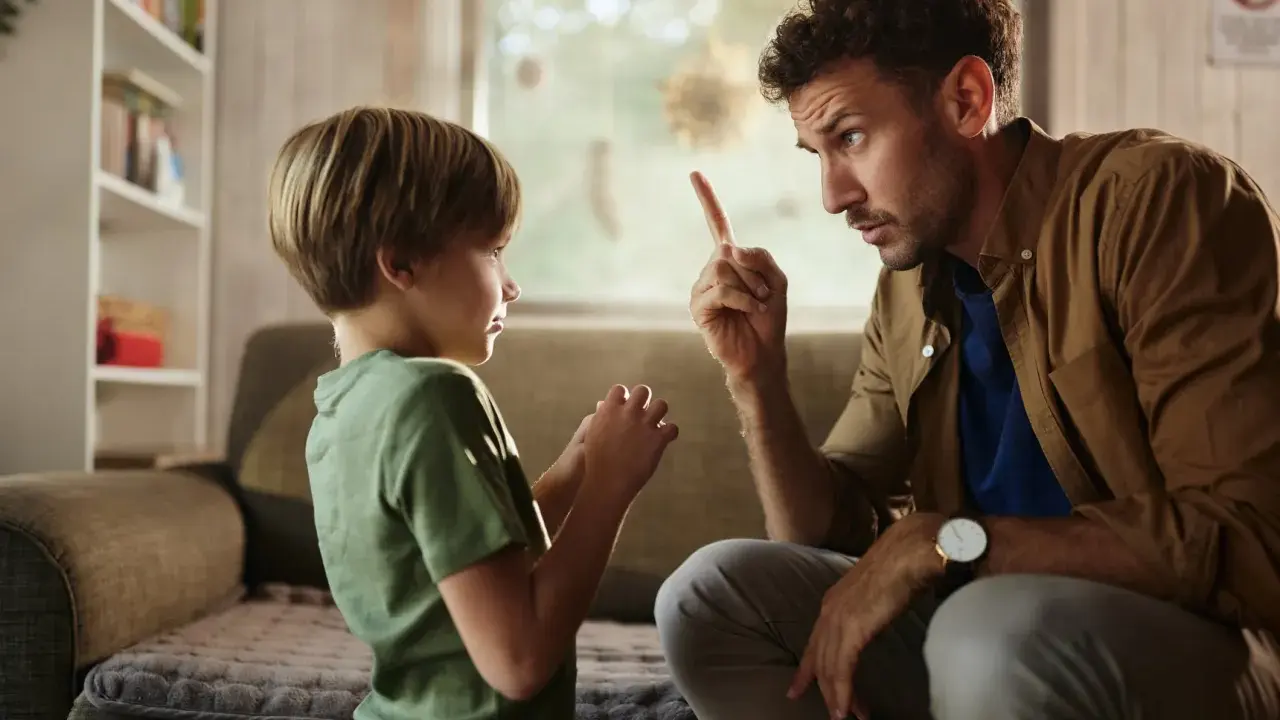 Un padre le dice no a su hijo, levantando el dedo índice en señal de advertencia. El niño escucha atentamente.