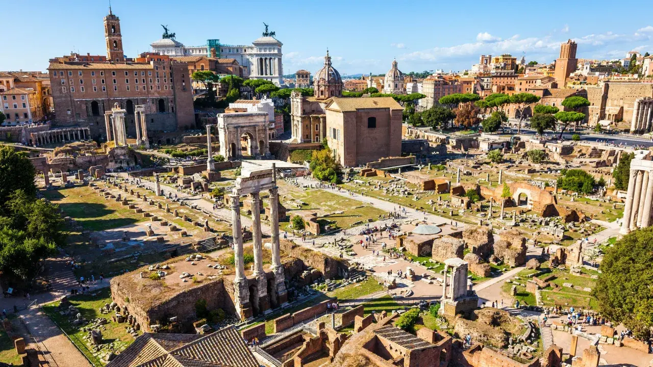 Antike Ruinen des Forum Romanum in Rom, 753 v. Chr. gegründet, mit Säulen, Bögen und Gebäuderesten unter blauem Himmel.