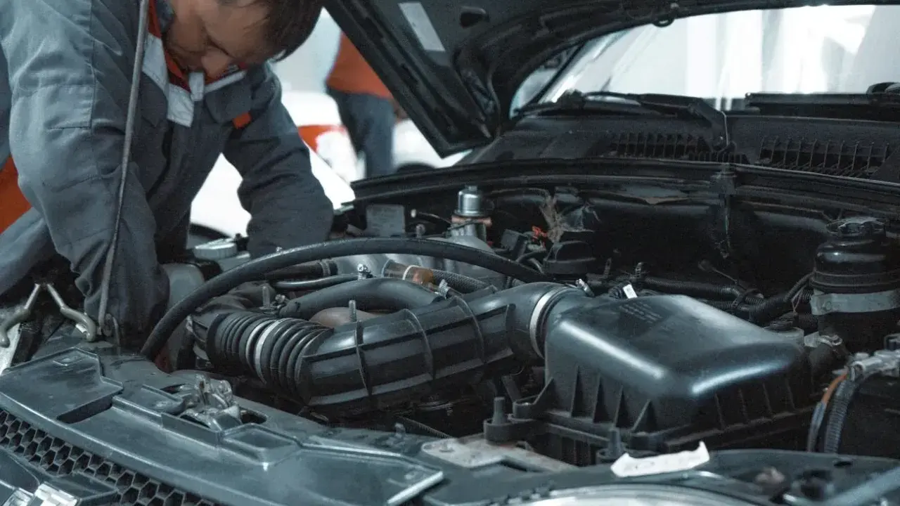 Mechanik pracuje przy silniku VW. Dowiedz się, ile kosztuje wymiana oleju w serwisie VW.