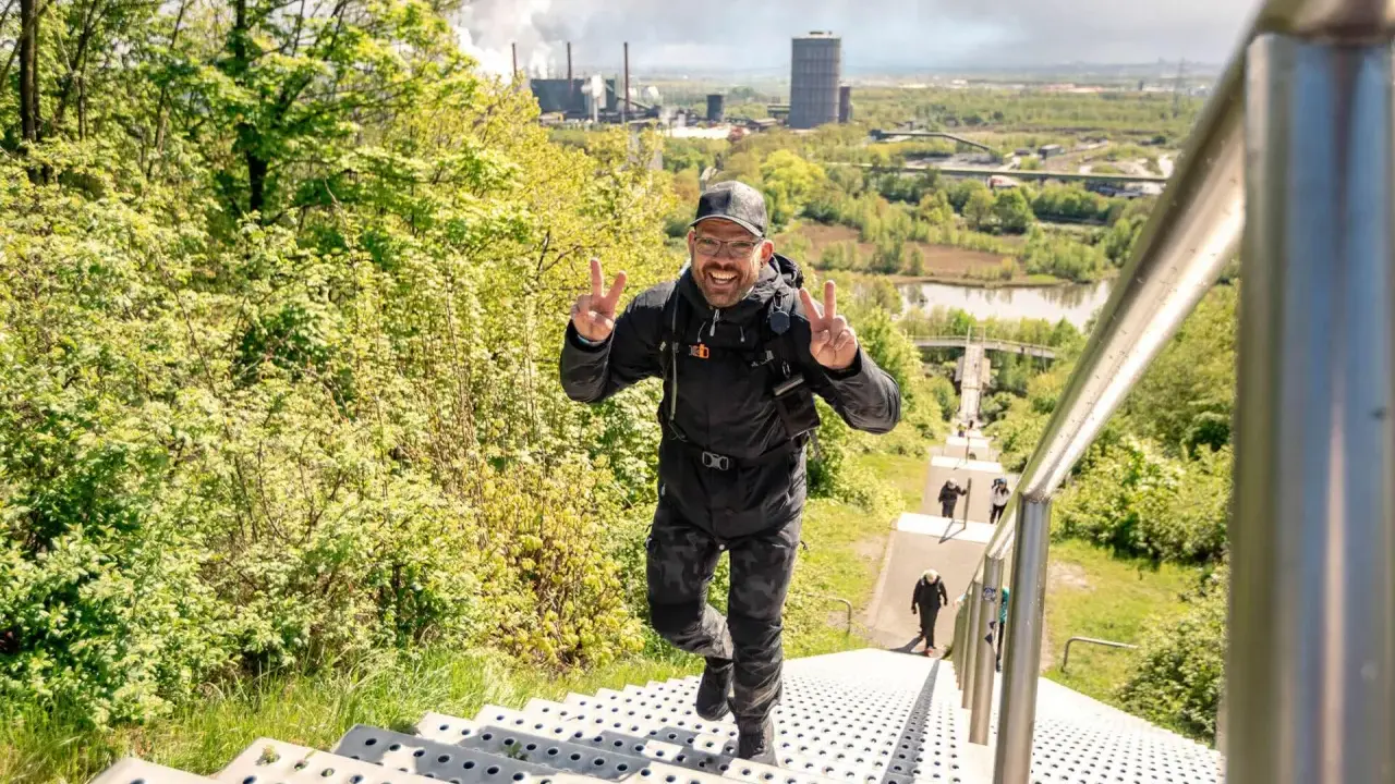 Glücklicher Mann erklimmt Treppen, genießt die Aussicht und verbrennt dabei Kalorien beim Wandern.
