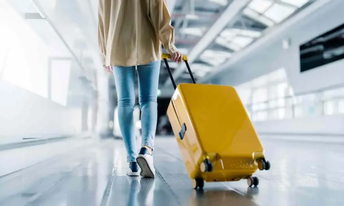 Person med gul resväska på rullband på ett av Sveriges flygplatser.