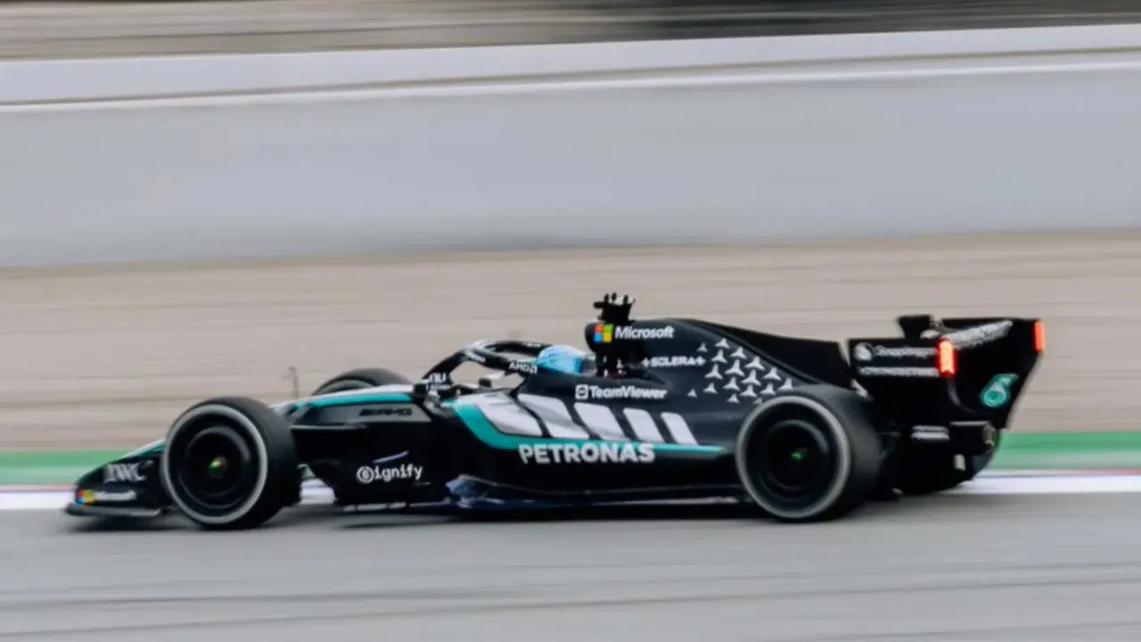 El Aston Martin AMR26 negro y turquesa acelera en la pista, con el logo de Petronas visible.