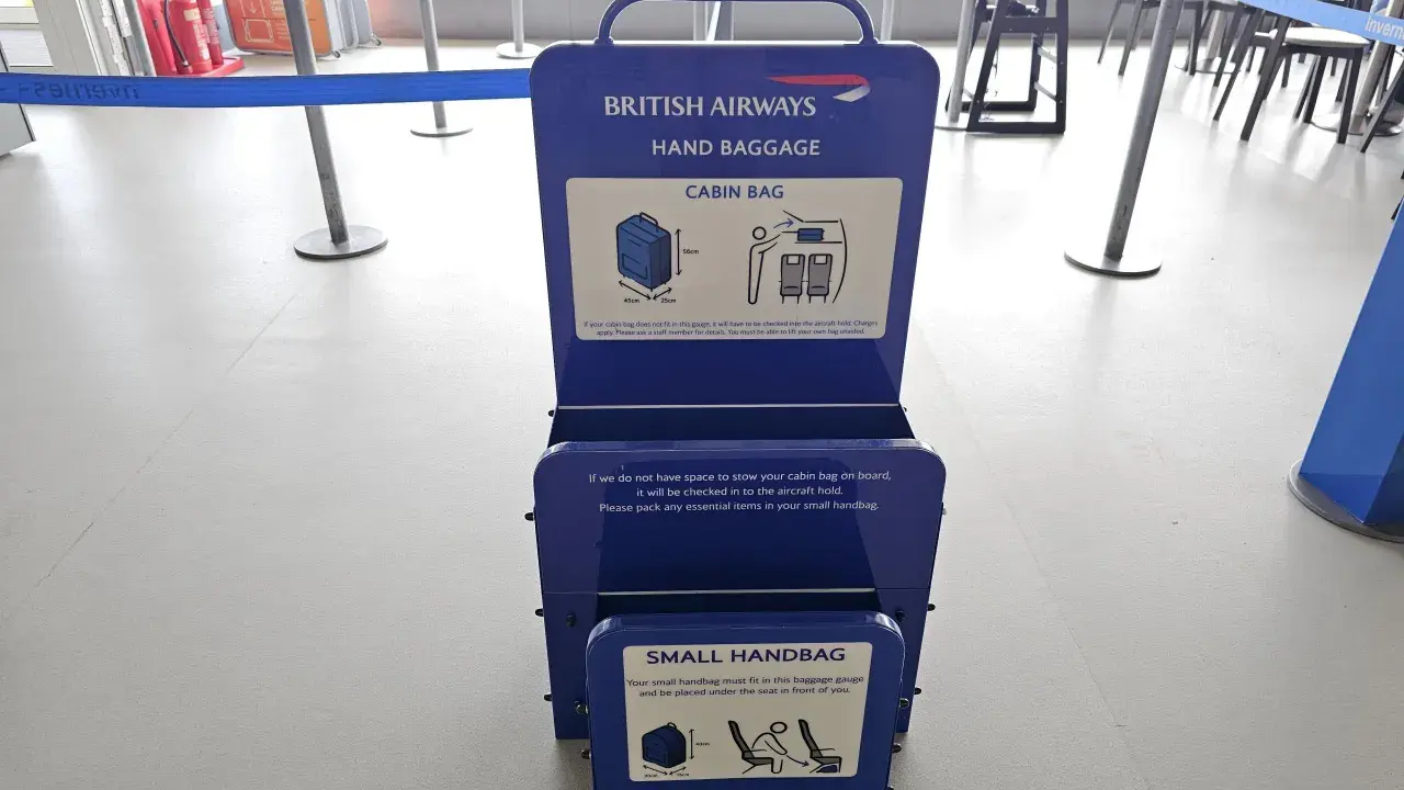 Niebieska miarka bagażu podręcznego British Airways na lotnisku. Sprawdź wymiary swojego bagażu kabinowego.