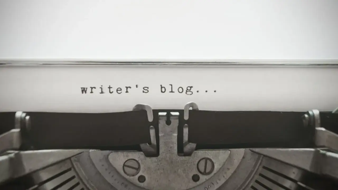 Maszyna do pisania z napisem "writer's blog..." na papierze. Idealny przykład wpisu na bloga po angielsku.