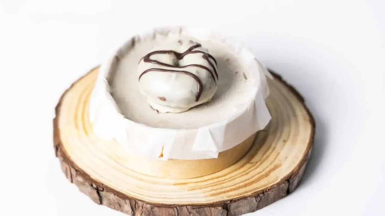 Deliciosa tarta de oro, cubierta de blanco y decorada con chocolate. Presentada sobre una base de madera rústica.