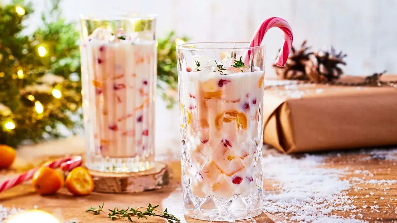 Festlicher Cocktail mit Kokosmilch, garniert mit einem Zuckerstangen-Lutscher und Früchten. Perfekt für die Weihnachtszeit.