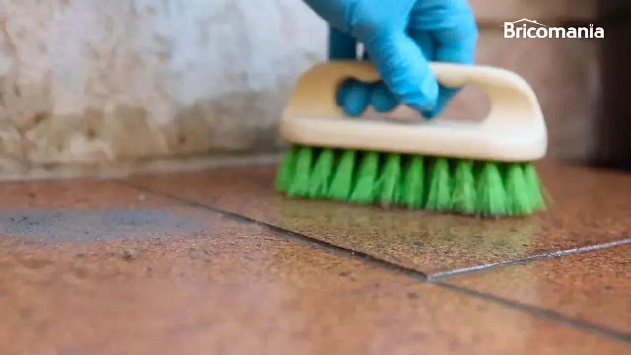 Guante azul cepilla suelo de baldosas para quitar cemento cola.