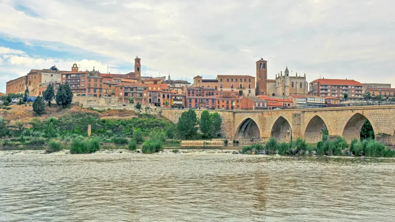 Un pintoresco pueblo con un puente de piedra sobre un río, ideal para visitar si buscas pueblos bonitos cerca de Valladolid.