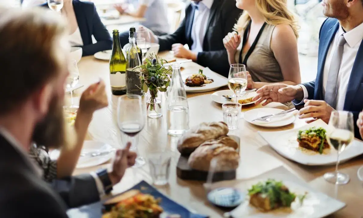 Un dîner sympa entre amis, avec des plats appétissants, du pain frais et du vin blanc sur une table en bois.