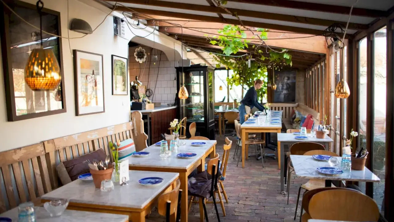 Mysig vinterträdgård med rustika bänkar och marmorbord, en av många annorlunda restauranger i Skåne.