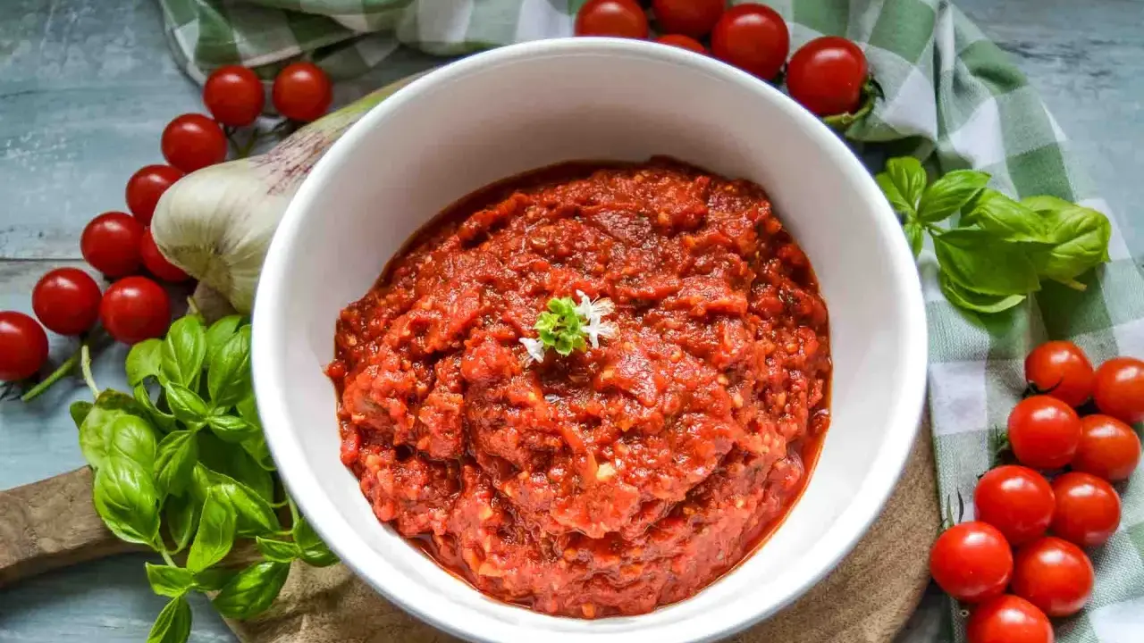 Frische tomaten pizza sauce, mit Basilikum und Knoblauch, umgeben von reifen Kirschtomaten.