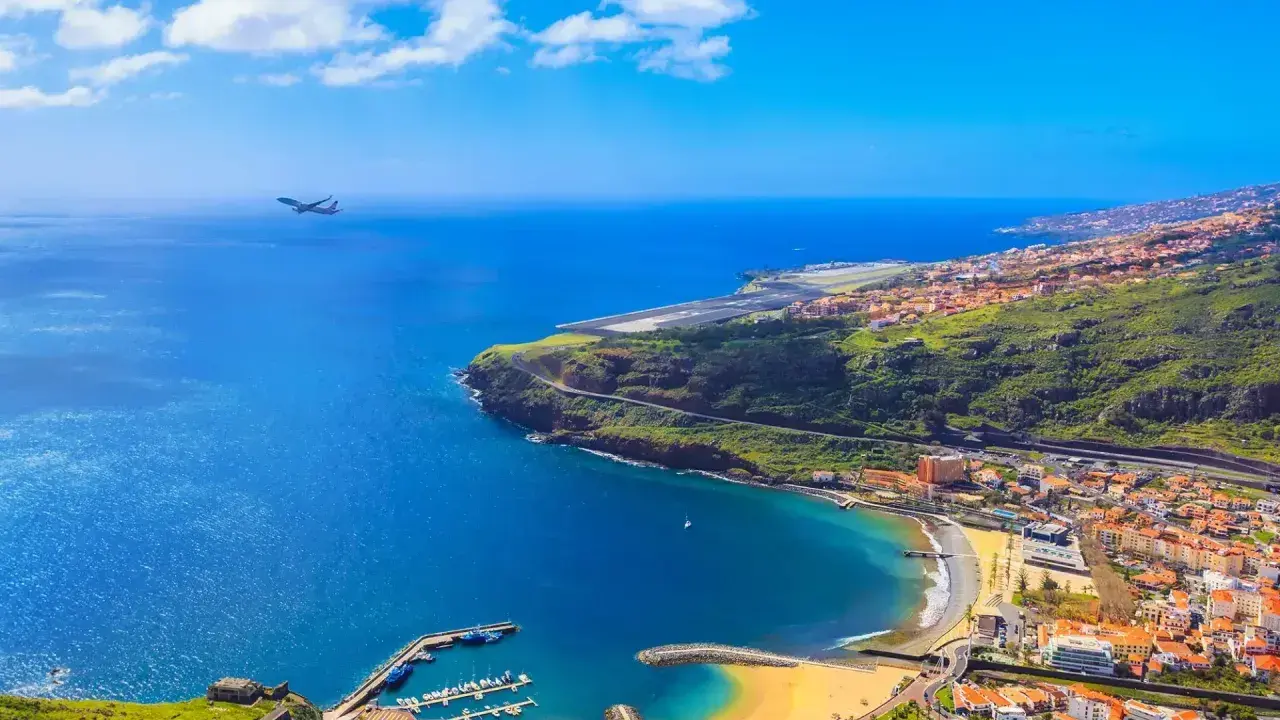 Widok na Funchal, kiedy na Maderę przylatuje samolot. Błękitne morze, plaża, port i zielone wzgórza.