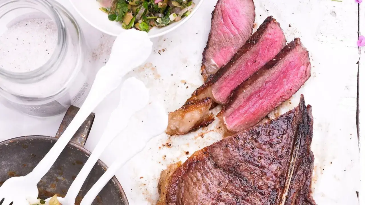 Perfekt gegrillter T-Bone-Steak, saftig rosa im Inneren, mit Beilagensalat und grobem Salz. Die t-bone steak zubereitung ist ein Genuss.