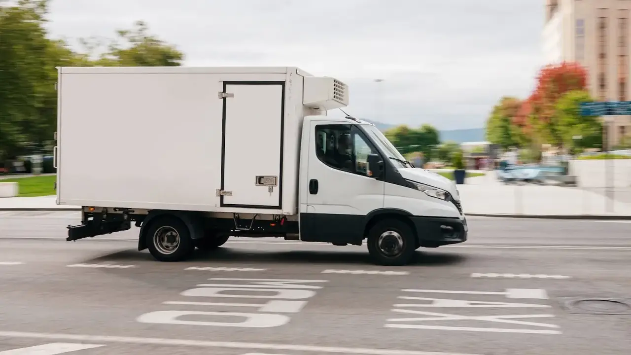 Biała chłodnia na podwoziu Iveco Daily, idealna do transportu towarów wymagających niskiej temperatury. Posiadanie prawa jazdy C1 pozwala na prowadzenie tego typu pojazdu.