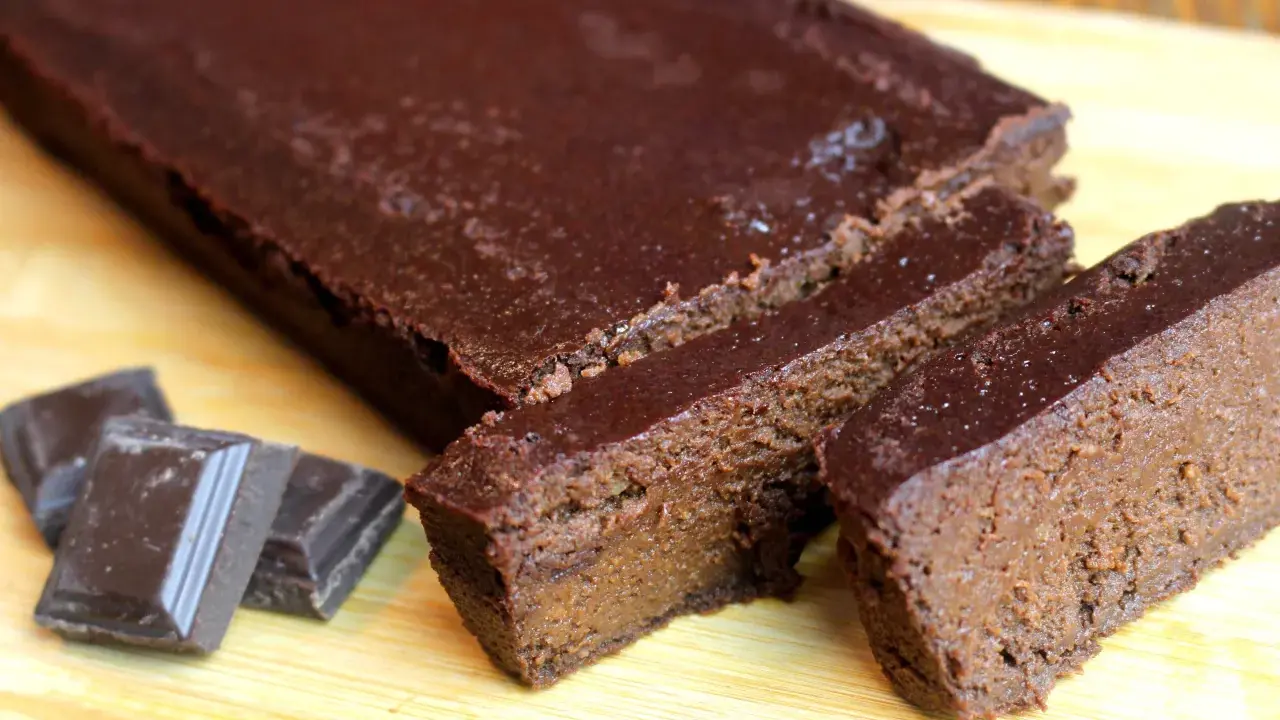 Un délicieux gâteau chocolat compote, coupé en tranches, avec des carrés de chocolat à côté.