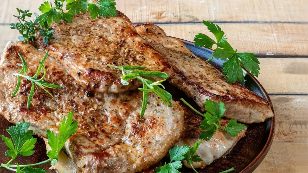 Soczysty schab z airfryer, idealnie przypieczony, podany z gałązkami rozmarynu i natki pietruszki. Pyszne i zdrowe danie.