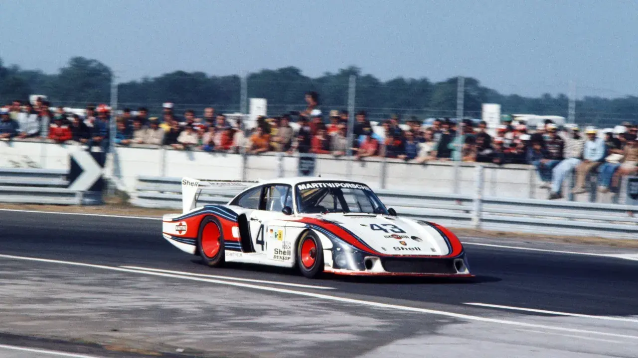 Der Porsche 935 "Moby Dick" rast auf der Rennstrecke, die Zuschauer jubeln.