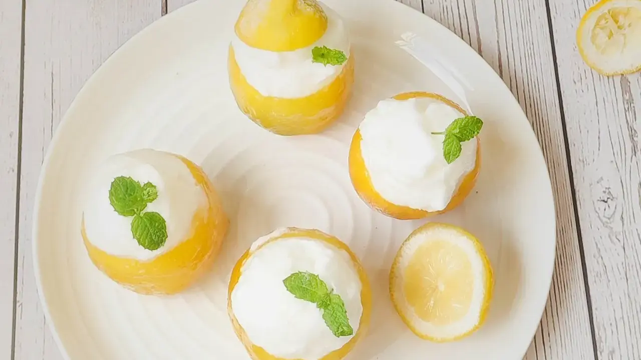 Quatre citrons givrés garnis de crème et de menthe, prêts à être dégustés. Un délice rafraîchissant !