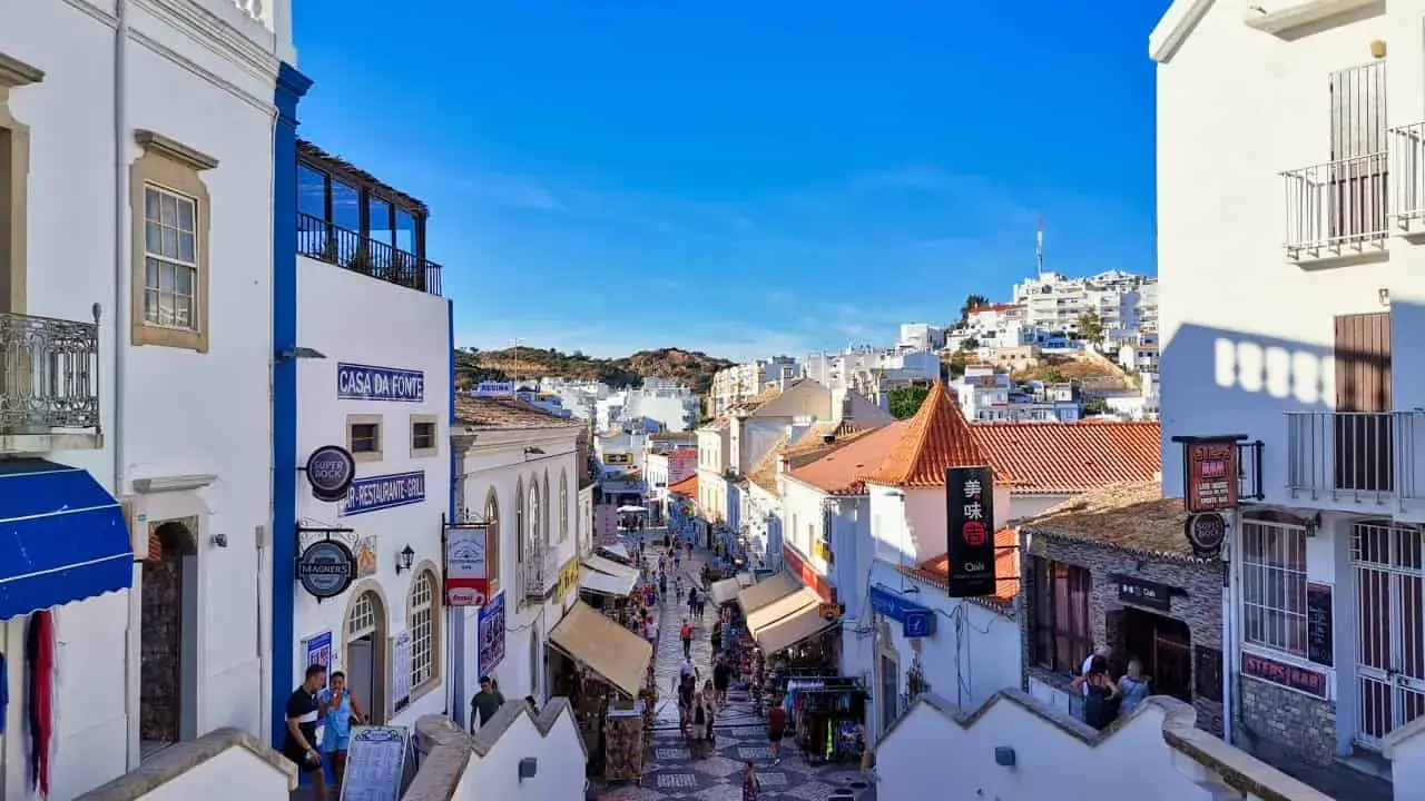 Bunte Gassen in Albufeira, Algarve, mit Geschäften und Restaurants, die sich den Hügel hinaufschlängeln.