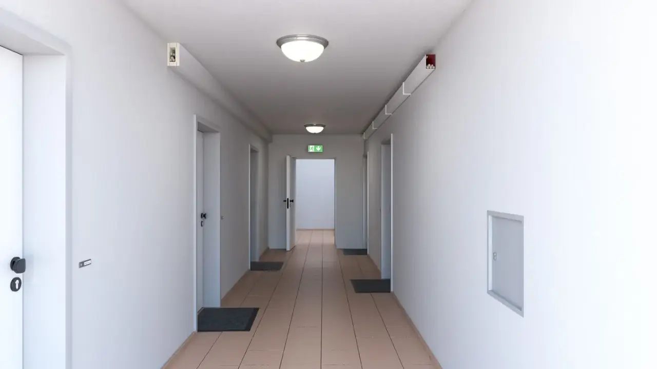 Ein langer, heller Flur mit mehreren Türen und einem grünen Notausgangsschild. Dieser notwendiger Flur ist gut beleuchtet und wirkt einladend.