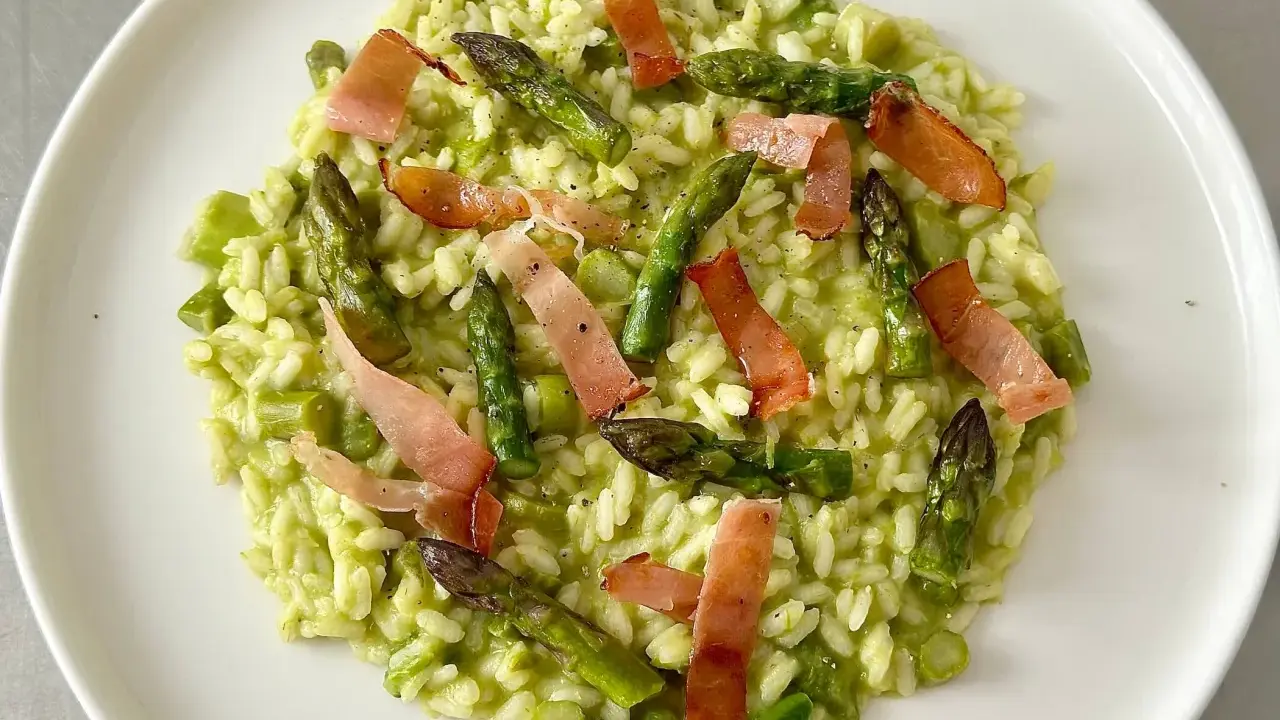 Risotto cremoso con asparagi freschi e croccanti strisce di speck, un piatto primaverile che delizia il palato.