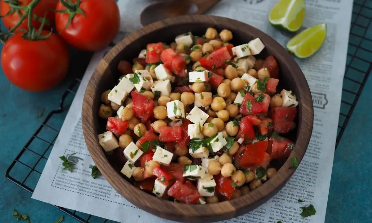 Ein köstlicher, **high protein salat** aus Kichererbsen, Tomaten und Feta in einer Holzschale, garniert mit Petersilie.